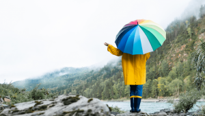 A person in a raincoat holds an umbrella